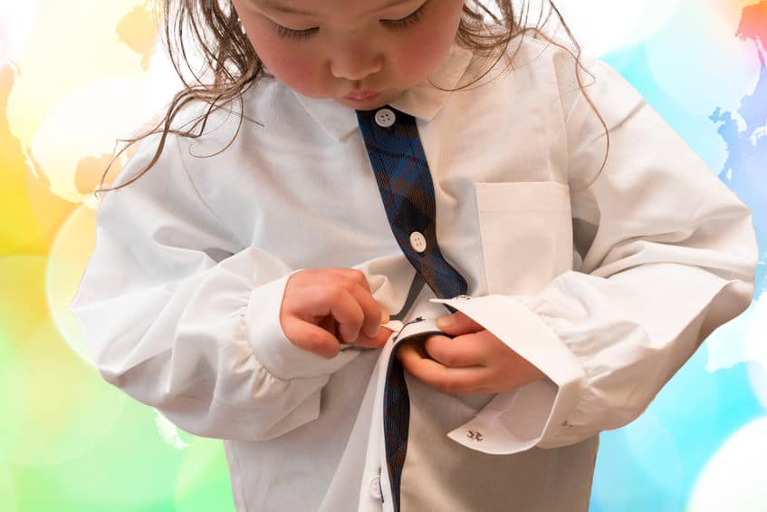 Fine motor development- self-confidence-independence-young girl working to button her shirt 