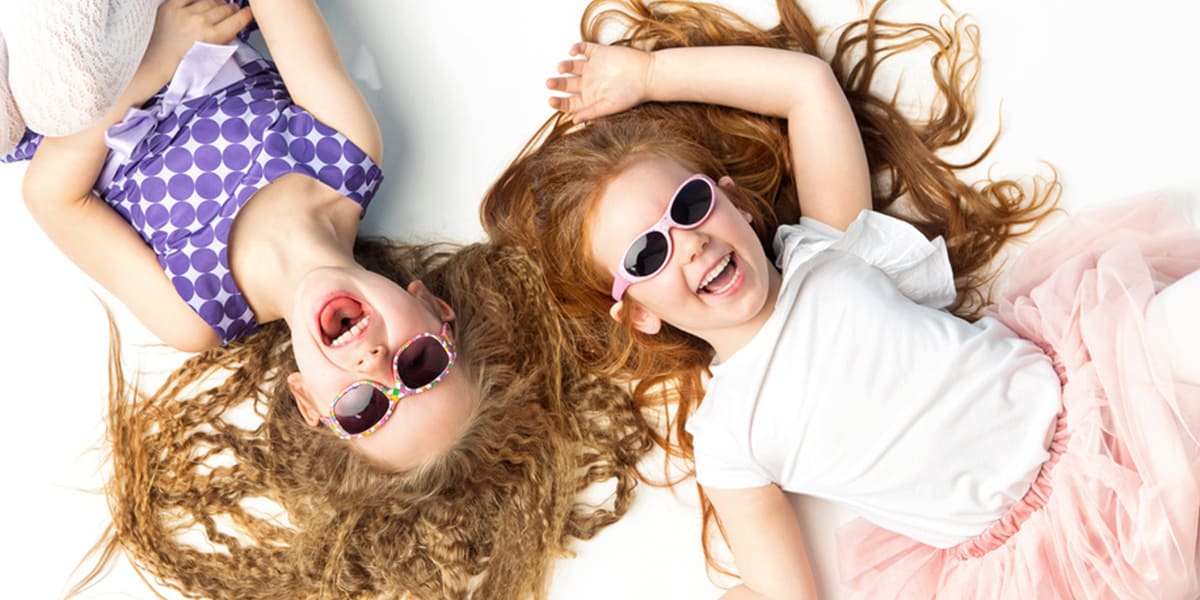 kids imagination-twin girls lying face up on the floor giggling