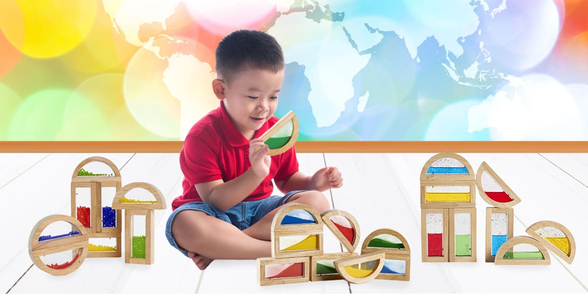 wooden stacking blocks-young boy playing with wooden building blocks that have clear windows filled with colored beads, sand or shimmering water