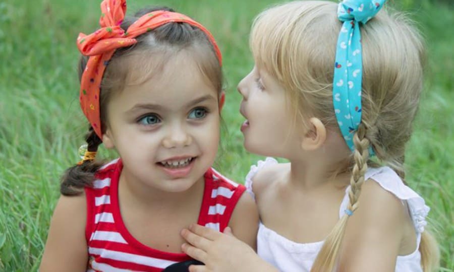 why are social skills important- two young friends sharing a secret