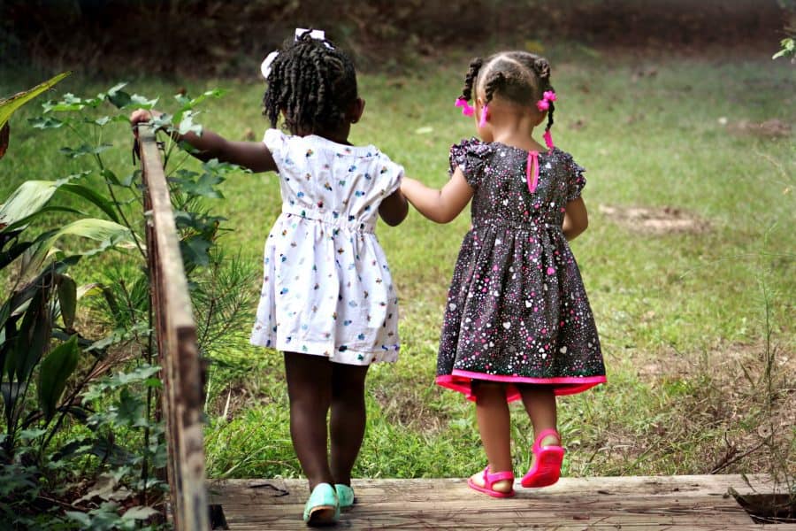social-emotional skills: friendship-two young girls crossing a bridge holding hands