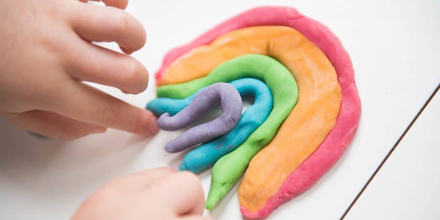 fine motor activities-preschooler hand molding a rainbow made from playdough