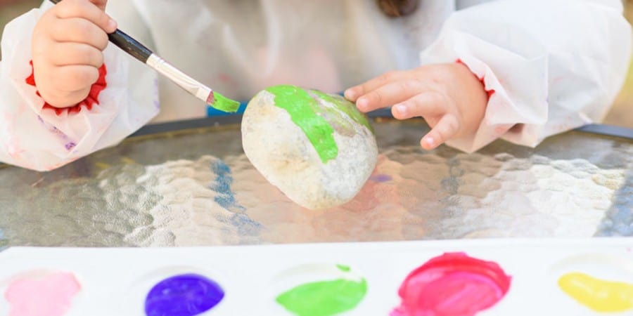 fine motor painting activities-young girl painting rocks with a brush