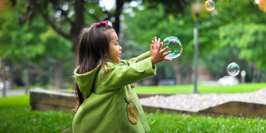gross motor activities for preschoolers-young asian girl chasing bubbles in the park