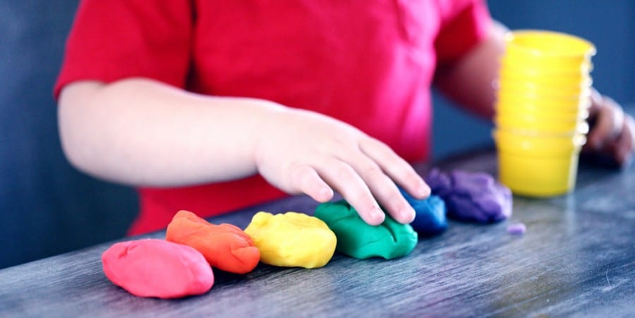 language activities for preschoolers-preschool boy playing with rainbow colors playdough