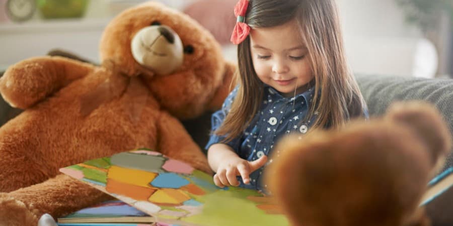 language activities for preschoolers-storytelling-young girl telling stories to her stuffed bears