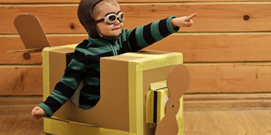 language development and imaginative play-toddler boy dressed as a pilot in a plane made from a cardboard box
