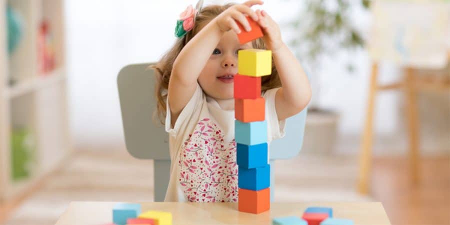 stem activities-engineering for toddlers-toddler girl building a tower with wooden square blocks