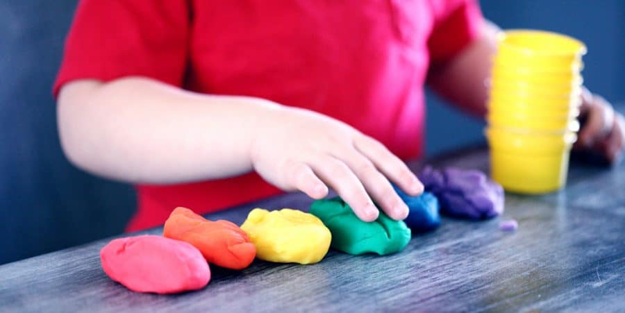 playdough stem activities-stem activities for toddlers-toddler at table with 6 piles of rainbow colored playdough