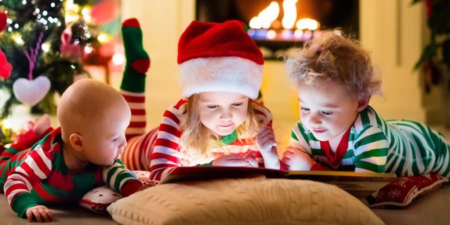 fun christmas activities-3 children reading a book in their christmas pajamas