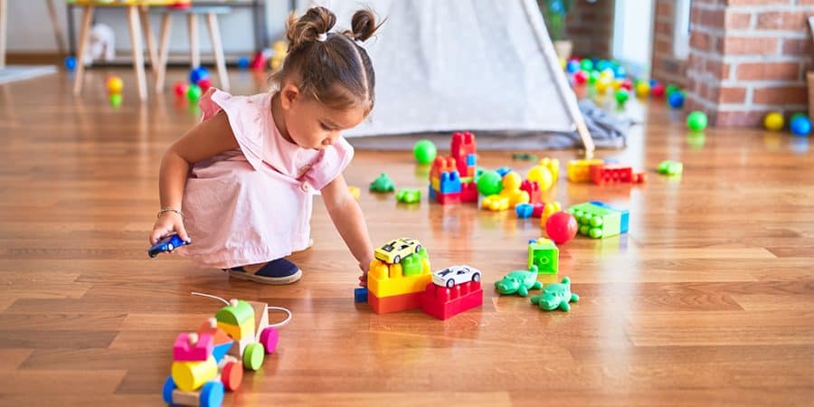 screen time for toddlers-importance of play for childhood development-you toddler girl playing with big building blocks and other open-ended toys