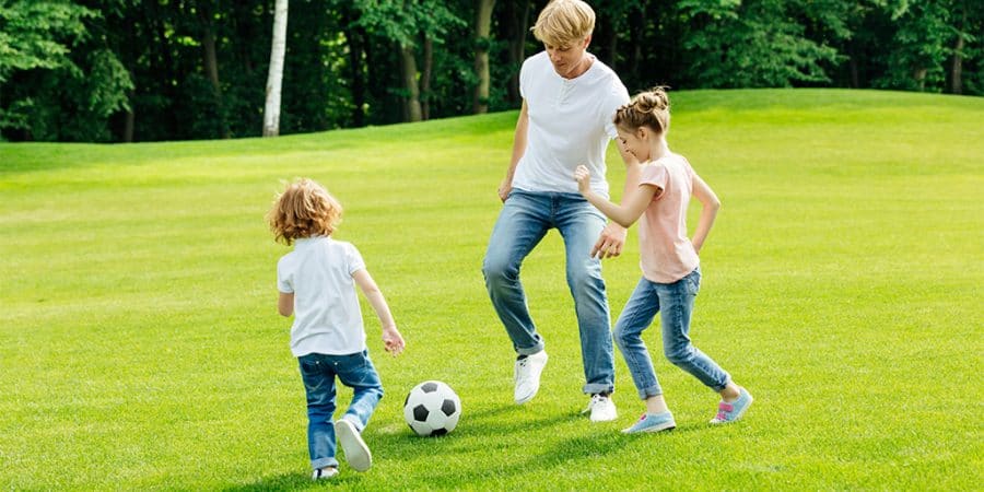 screen time alternative-father playing soccer with son and daughter in a park