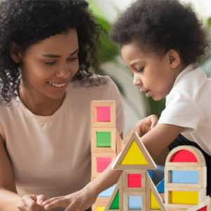 learning through play activities - young black son and mother playing with wooden building blocks